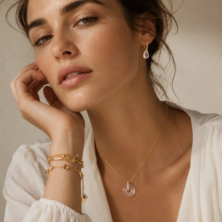 Woman Wearing Rose Quartz Jewelry Set and Layered Gold Bracelets